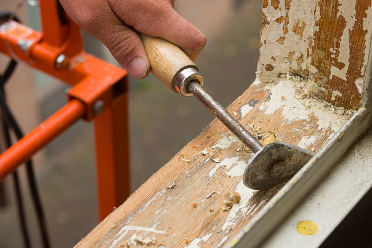 A painter removing old paint with a scraper