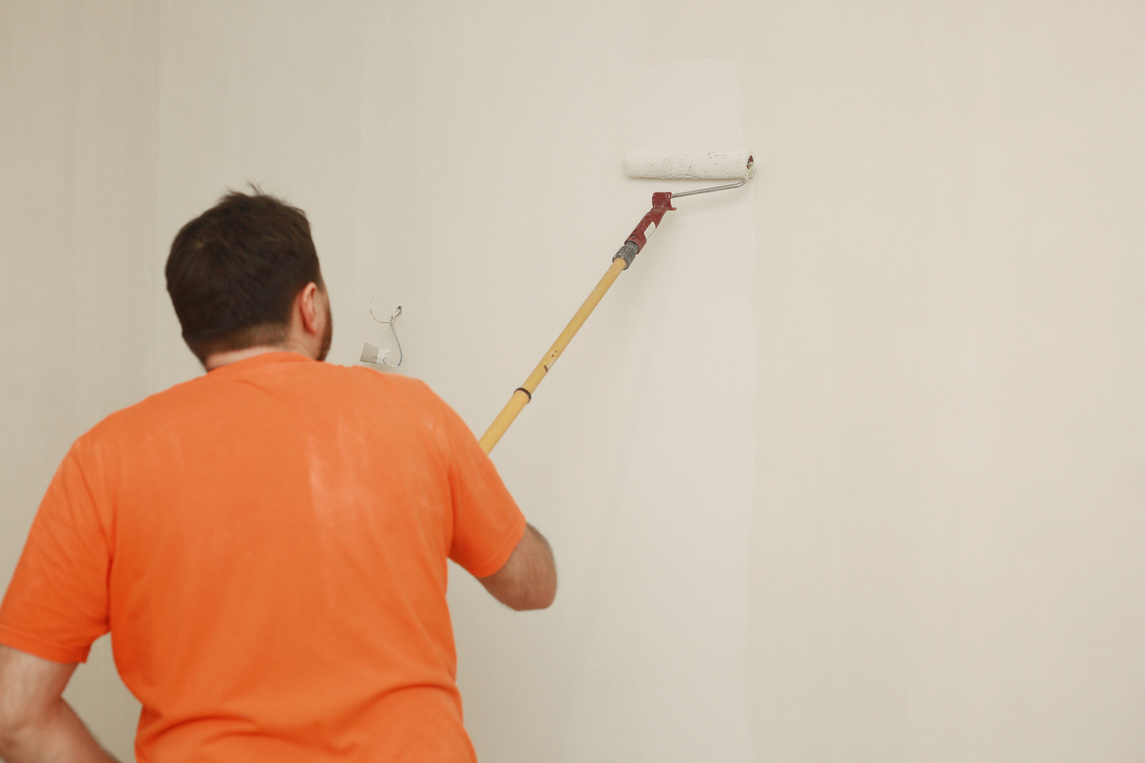 Male painting wall with paint roller by a professional painter in the Tracy area