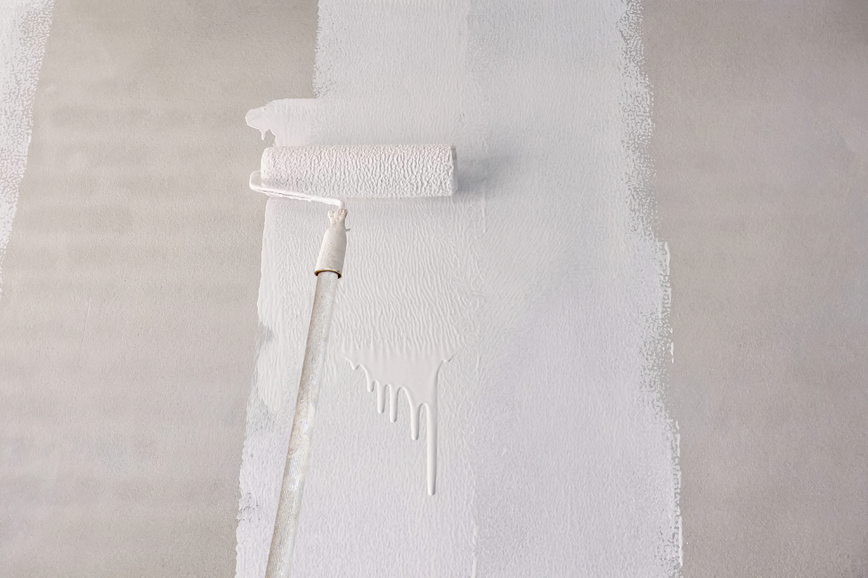 Painting primer white color on concrete wall with long handle roller brush in construction site in Livermore