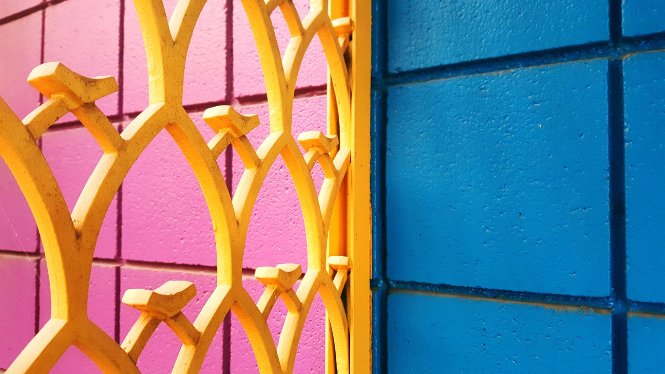 Colorful pink and blue brick wall with a decorative yellow iron metal gate in the Livermore area